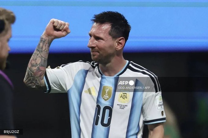 Soccer player Lionel Messi, wearing the Argentina national team jersey with the number 10, celebrates with a raised fist; the photo is credited to Odd Andersen/AFP.