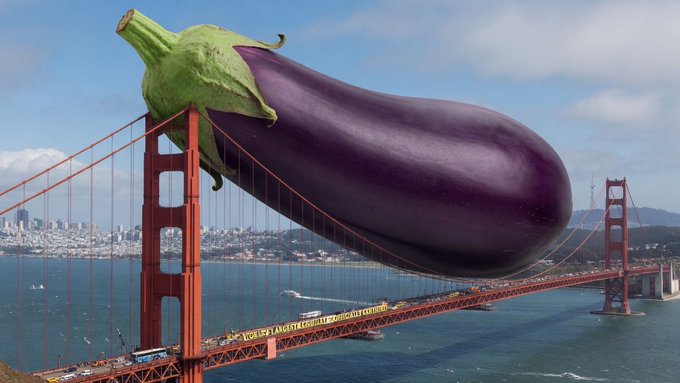 The image features a large purple eggplant that has been placed on top of a red suspension bridge, with the bridge spanning across a body of water such as an ocean or lake. The eggplant appears to be floating above the water, creating a unique and interesting scene. The caption for this image reads "The best is yet to come @XPRNetwork". This suggests that there might be more content related to the eggplant on display in the future, possibly including photos of other unusual objects or scenes.