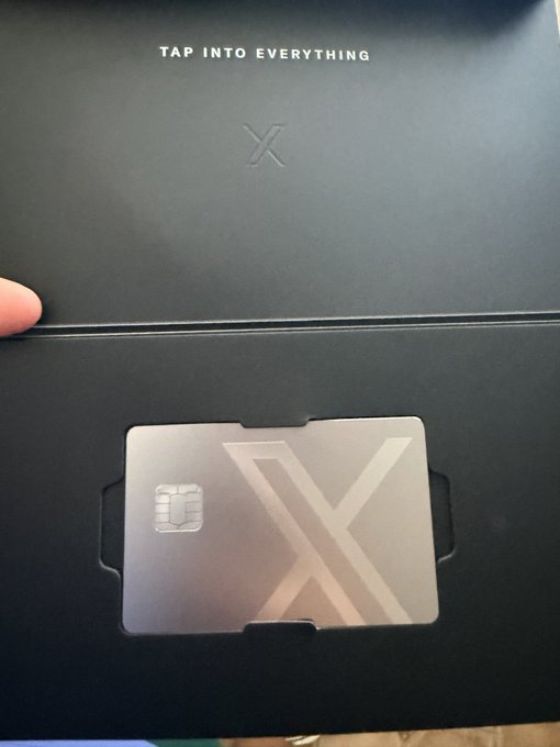 An open black packaging envelope with 'TAP INTO EVERYTHING' printed on it reveals a metallic X-branded card with a chip.