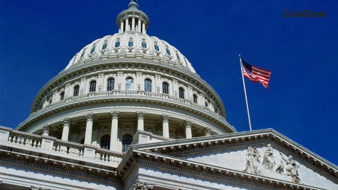 The U.S. Capitol dome stands against a clear blue sky with an American flag waving beside it, symbolizing the legislative backdrop for the upcoming Senate vote on September 15 regarding the contested stablecoin rewards provision in the Clarity Act.