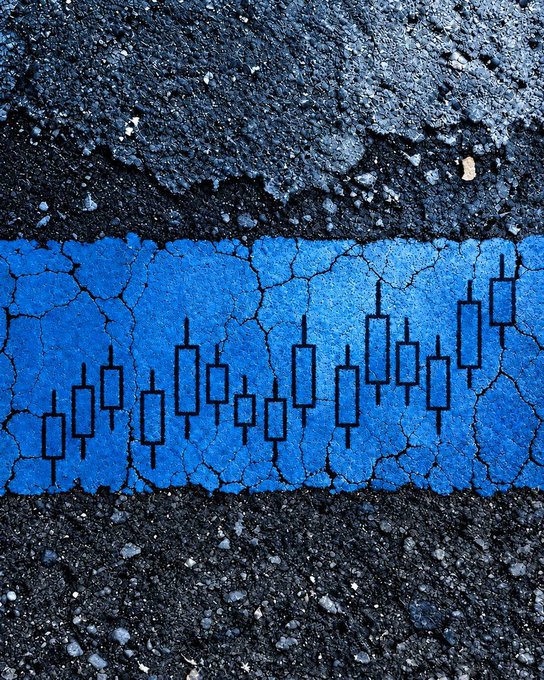 A blue painted road marking between sections of asphalt features a row of candlestick chart patterns, humorously transforming an ordinary lane divider into a trader's price action chart.