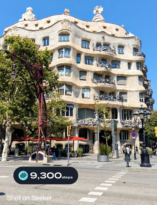 A photograph of Casa Milà (La Pedrera) in Barcelona, an iconic Gaudí building with a wavy stone facade, with a '9,300 steps' overlay indicating it's a screenshot from the Seeker app.