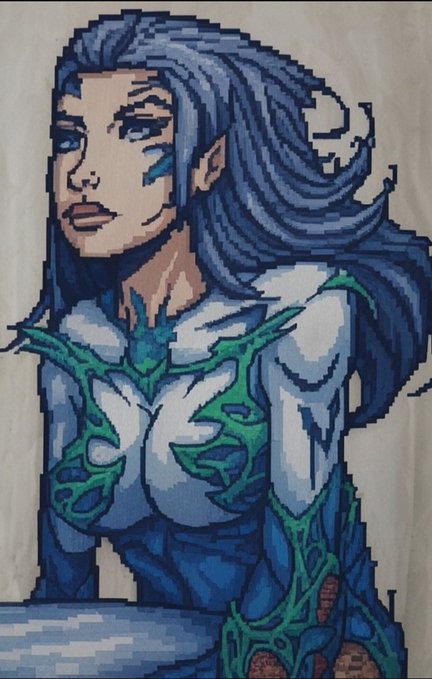A pixel art illustration of a female character with long flowing blue hair and a white and green organic-patterned outfit.