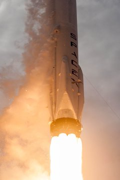A SpaceX rocket lifts off with fiery thrust billowing beneath it, visually symbolizing the company's powerful ascent—mirroring the soaring momentum and massive institutional inflows anticipated as SpaceX joins the Nasdaq-100 shortly after its IPO.