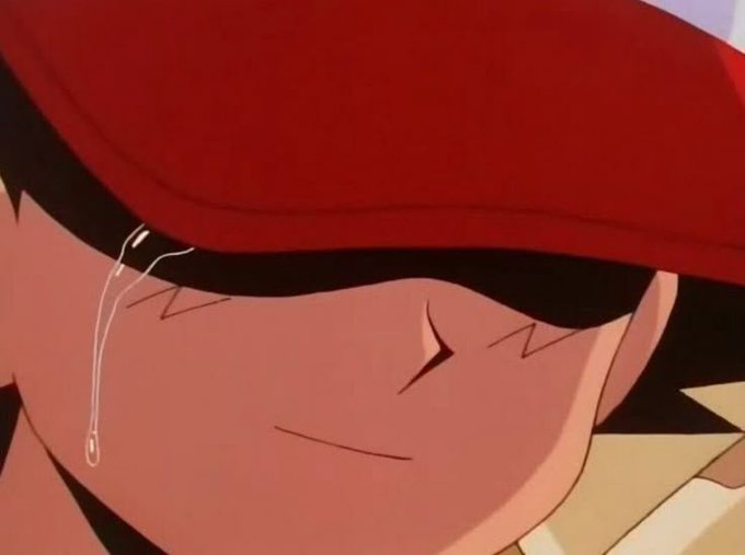 A close-up anime scene of a character wearing a red cap with a sad expression and a single tear.