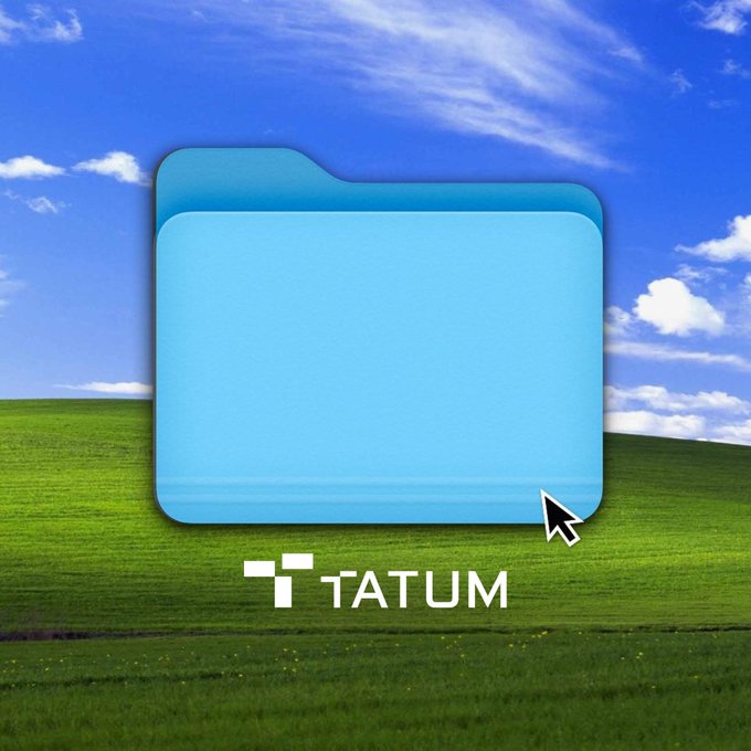 A blue folder icon displayed over the classic Windows XP 'Bliss' wallpaper (green hills and blue sky), with the 'TATUM' logo and a cursor arrow below the folder.