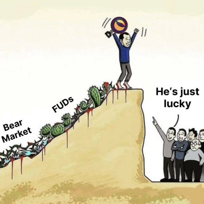 The image features a cartoon depiction of a man standing on top of a hill, holding up an orange sign with his arms raised high above his head. The man appears to be celebrating or making a statement about something related to cryptocurrency. In the background, there are several other people who seem to be part of this scene as well. The image also includes text that reads "The biggest comeback in crypto wouldn't just be a win for $LUNC holders—it would be a testament to the people who kept building, supporting, and believing when most had written it off". This suggests that the man's actions could represent a significant event or milestone related to cryptocurrency.