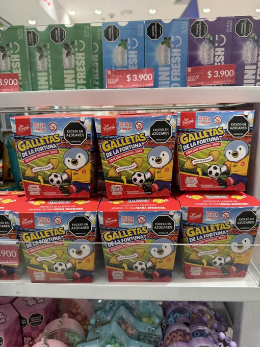 Shelves in a store display boxes of 'Galletas de la Fortuna' fortune cookies and 'Mini Fresh' breath mints priced at $3.900, both marked as containing zero sugar ('Excesos en Azúcares').