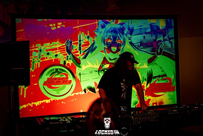 A DJ wearing a cap performs behind Pioneer equipment in front of a vibrant green and red screen featuring anime artwork and a 'LOCKHER' logo.