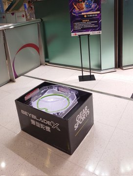 A Beyblade X 'Stadium' display box sitting on the floor of a store or mall.