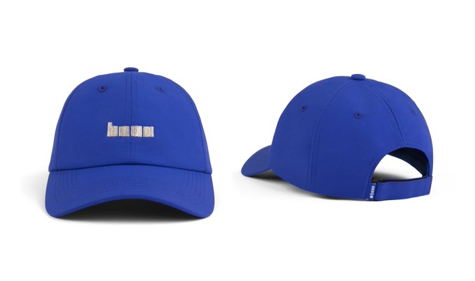 A royal blue baseball cap displayed from front and back angles, featuring the word "market" embroidered in small white text on the front panels, tying into the "Market Cap" theme of the post.
