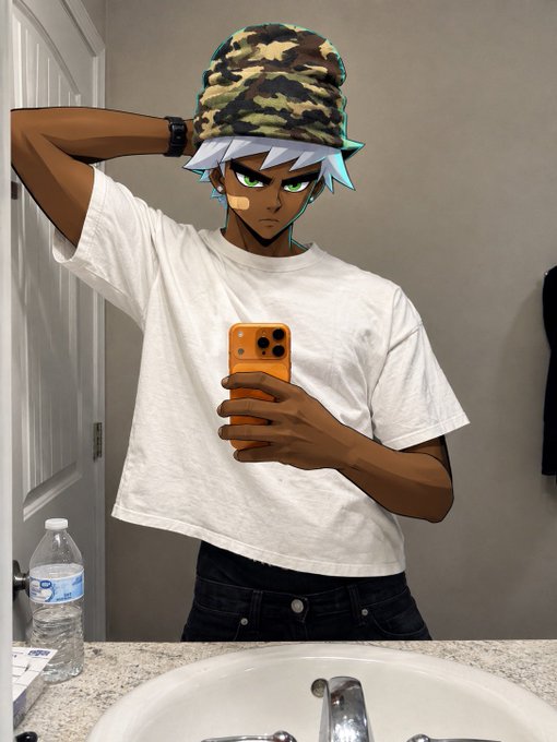 A person takes a mirror selfie in a bathroom wearing a white t-shirt, dark jeans, and a camouflage bucket hat, while their anime-style face (featuring silver hair and green eyes) has been edited onto their head. An orange phone is held up to capture the photo, with a water bottle visible on the sink counter — a casual "gm X" post to greet followers for the new month.