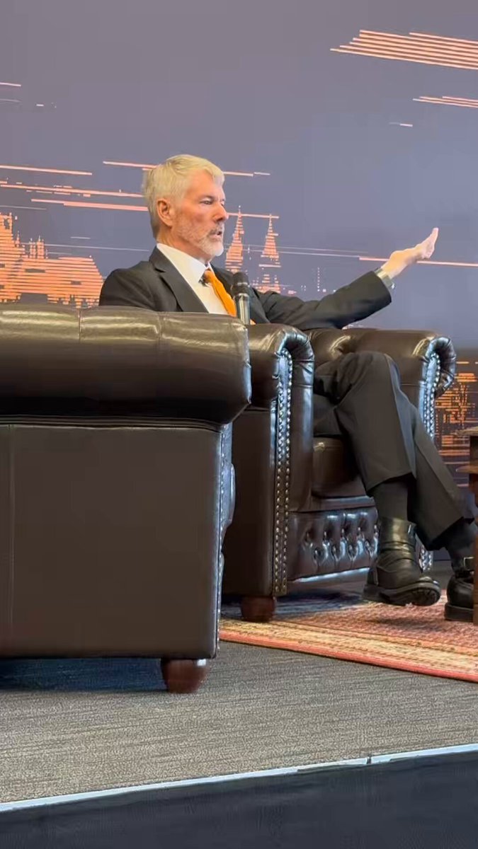 The image features a man sitting in a chair with his arm outstretched as if he's giving a speech or making an announcement. The background of the image shows a large picture hanging on the wall, which appears to be a painting depicting a city skyline. The caption below the picture reads "NEW: Michael Saylor explains his 32 $BTC sale, I said to you never sell your Bitcoin, I never said that the company wouldn't sell its Bitcoin." This suggests that there might have been an event or announcement related to cryptocurrency in the past, and the man is now sharing some information about it.

The image also contains a chair positioned behind the man, which he's sitting on. The chair appears to be made of leather with a brown color.