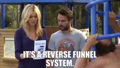 A screenshot from a TV show showing two people at a playground, with the caption 'IT'S A REVERSE FUNNEL SYSTEM.'