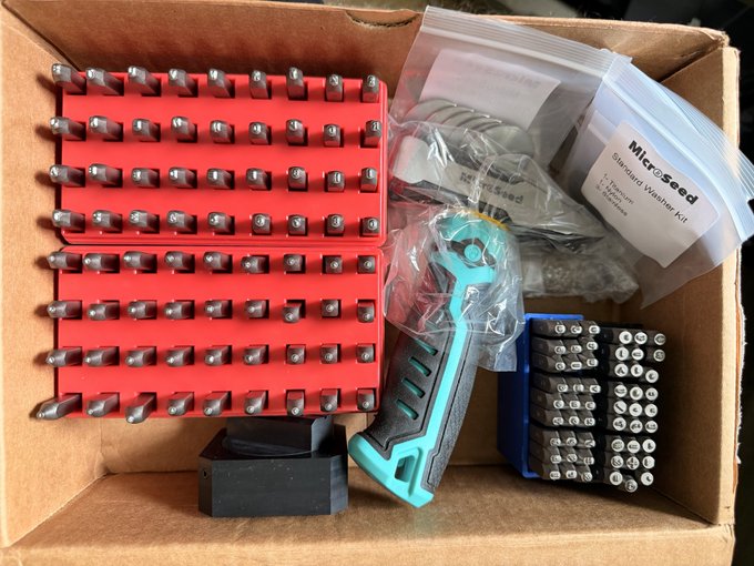 A cardboard box containing a Microseed Standard Washer Kit with red bit holders, a teal ratchet handle, assorted bits, and a cleaning cloth.
