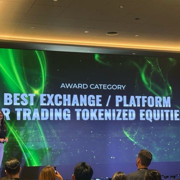 A stage screen displays 'AWARD CATEGORY: BEST EXCHANGE / PLATFORM FOR TRADING TOKENIZED EQUITIES' with an audience visible in the foreground watching the presentation.