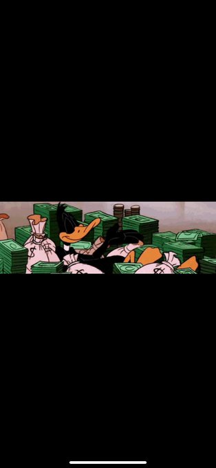 An animated scene featuring Daffy Duck lounging in a pile of money bags, surrounded by stacks of green cash.