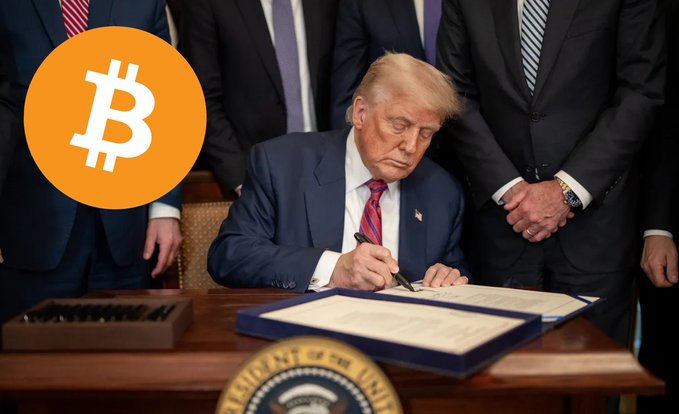 A man with blonde hair in a dark suit and red tie signs documents at a desk bearing the Presidential seal, surrounded by officials, with an orange Bitcoin logo overlaid in the corner—visually tying executive action to potential crypto legislation such as the CLARITY Act.