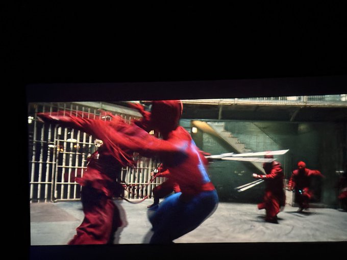 A person in a Spider-Man costume is shown in mid-combat on a movie screen, fighting against masked opponents wielding swords, likely a scene from a Spider-Man film. The image relates to the post by illustrating the costly movie ticket (40 yuan) the author recently purchased, an expense they're now second-guessing given significant losses in US stock investments.