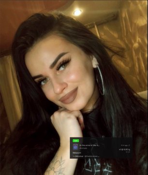 A close-up selfie of a smiling young woman with long dark hair wearing large hoop earrings, with a small chat overlay visible at the bottom of the image.