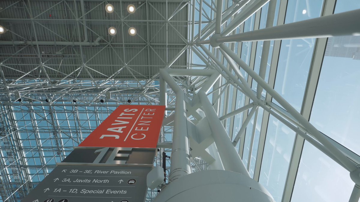 The image shows a large glass ceiling with multiple levels of support beams that create an impressive architectural structure. The ceiling appears to be part of a building, possibly a convention center or a large event space. A sign is prominently displayed at the top of the ceiling, which reads "Jantas Center". Below this sign, there are several other signs providing information about upcoming events and speakers.