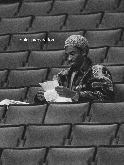 A black-and-white photo of a man in a leopard-print jacket and skullcap reading papers while seated alone in an auditorium, with the text "quiet preparation" overlaid on the image.