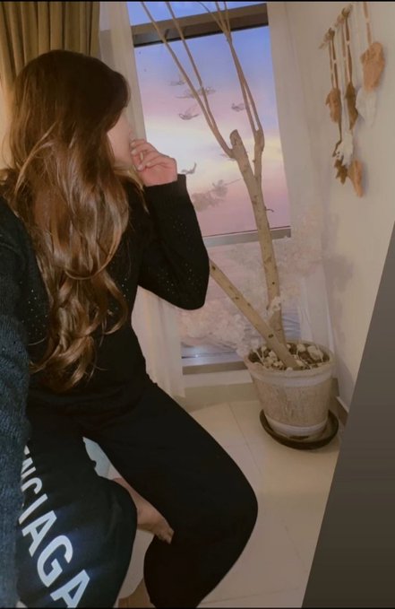 A woman in black Balenciaga sweatpants gazes out a window at a sunset view, contemplating her trading future with $BNB. The caption reads "Good night everyone — Is 1 $BNB enough for you to start your trading journey? Tell me," paired with the serene evening scene as she reflects on the question.