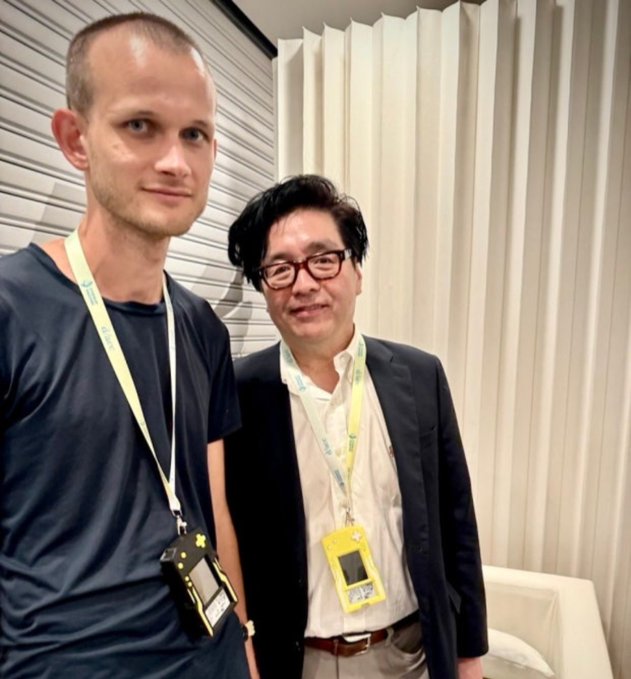 Two men pose together at what appears to be a conference, with the man on the right wearing a yellow lanyard credential and glasses, likely representing Tom Lee of Bitmine (BMNR) following his bullish comments on Ethereum's future performance against Bitcoin.