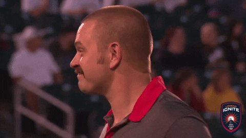The image shows a man with a mustache wearing a gray shirt, standing in front of an audience at a sporting event. The background reveals that there are multiple people watching the game from various positions around the field. The caption for this image reads "Good Evening friends Altseason 3.0 loading..... $RIVER @River4fun @RiverdotInc @XOOBNetwork".