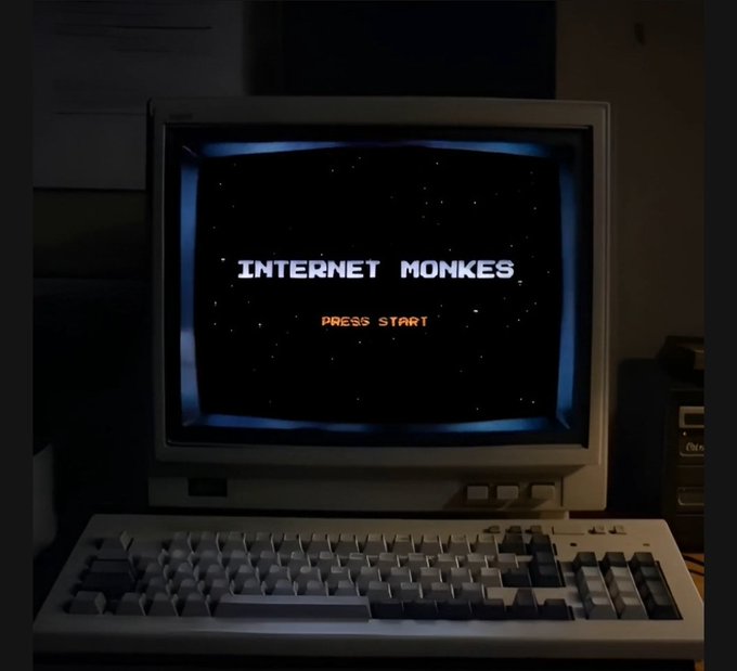 A vintage CRT monitor displaying 'INTERNET MONKES - PRESS START' in retro pixel font on a starfield background, sitting above a beige mechanical keyboard.