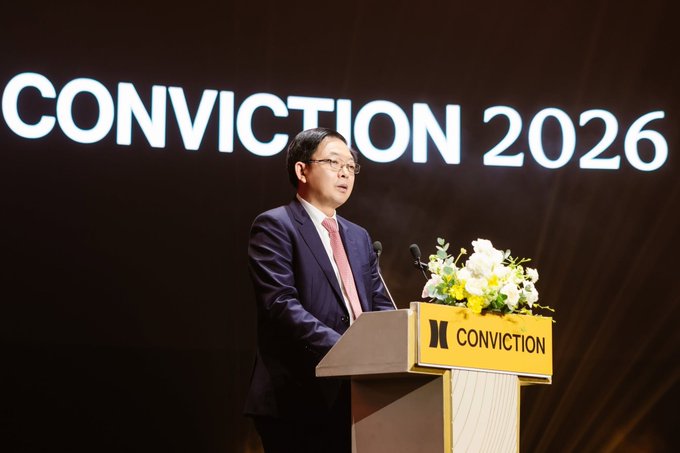 A man in a navy suit and pink tie speaking at a podium at the 'CONVICTION 2026' conference, with the event's large logo displayed on screen behind him.