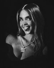 A black-and-white portrait photograph of a smiling young woman with long hair, wearing a necklace with a pendant, set against a dark background.