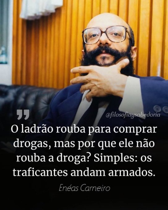 A bald man with glasses and a beard in a blue suit poses thoughtfully; the quote reads 'O ladrão rouba para comprar drogas, mas por que ele não rouba a droga? Simples: os traficantes andam armados.' by Enéas Carneiro.