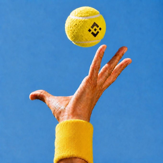 The image features a person's hand wearing a yellow wristband, with their thumb raised high above their head as they attempt to catch a tennis ball that is floating in the air. The background of the photo shows a clear blue sky, which complements the vibrant colors and energetic atmosphere of the scene. The post includes an image of a yellow tennis ball and a black dragon boat logo, suggesting a connection between the sport of tennis and the Dragon Boat Festival.