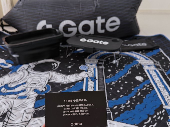 A Gate.io promotional merchandise set including a 'Gate' branded bag, black container, towel with astronaut design, and a Chinese-language card referencing 'Moon River'.