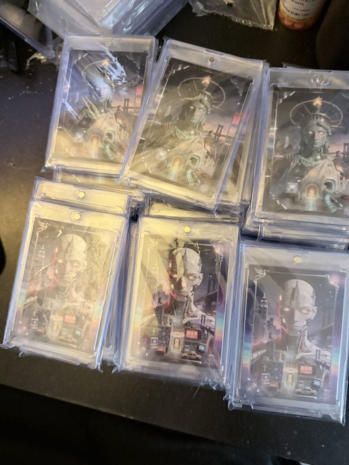 Multiple stacks of trading cards in protective plastic sleeves featuring dark, gothic-style artwork of statues with glowing eyes and intricate architectural designs.