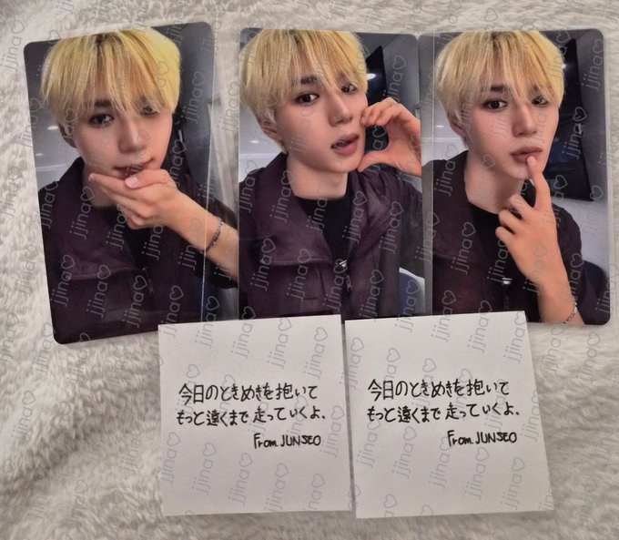 Three photocards of a blonde-haired K-pop idol, watermarked 'Jina' with hearts, alongside two handwritten notes in Japanese reading '今日のときめきを抱いて もっと遠くまで走っていくよ。 From JUNSEO'.