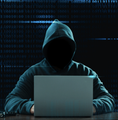 A hooded figure sits in front of a laptop in a dark, moody setting with digital code displayed in the background.