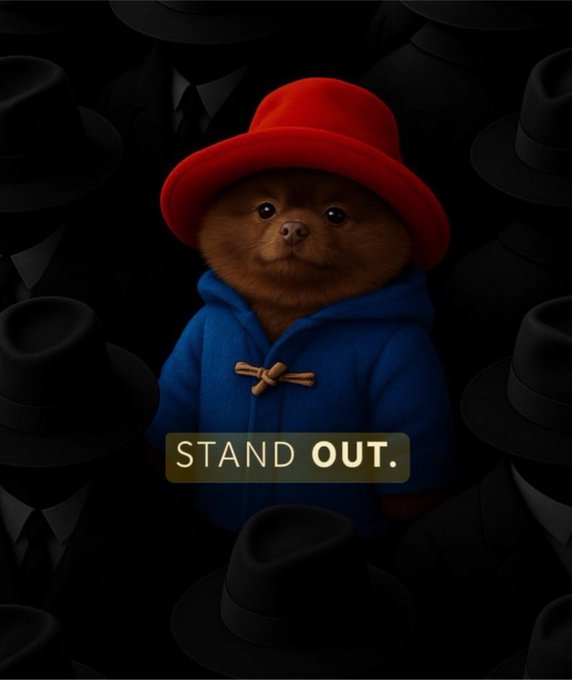 A Paddington Bear-style bear wearing a bright red hat and blue duffle coat stands out vibrantly against a dark background filled with shadowy figures in black suits and hats, with the text "STAND OUT." displayed prominently. The image's message of standing out visually reinforces the celebratory post about BertCoin's one-year partnership anniversary with KuCoin, highlighting how the project distinguishes itself by delivering major exchange listings and a nearly year-long staking program.