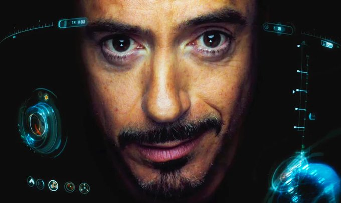 A close-up of Tony Stark inside the Iron Man helmet with HUD displays surrounding his face, fitting the post referencing "Jarvis"—the AI assistant Stark famously uses to set reminders and manage his tech, here applied to reminding him to watch *Avengers: Doomsday* on December 18th.