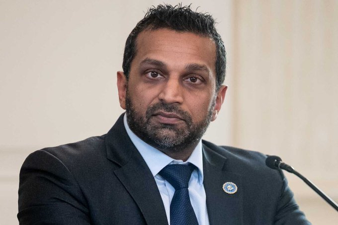 The image features a man wearing a suit, tie, and blue shirt with a microphone in front of him. The man appears to be speaking or giving a presentation at an event. In the background, there are two microphones placed close together, suggesting that this is a public speaking event or a press conference. The text "BREAKING: FBI Director Kash Patel says the FBI will find crypto scammers and bring them to justice." indicates that the man in the suit has made some significant announcements related to law enforcement actions against crypto scammers.
