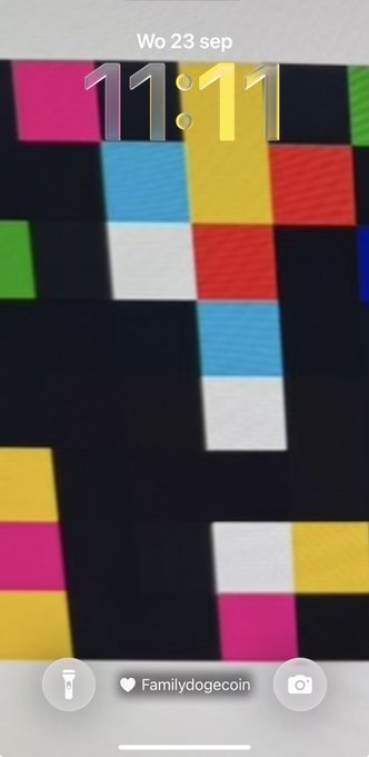 A phone lock screen displaying '11:11' over a colorful Tetris-like wallpaper, with 'Wo 23 sep' at the top and a 'Familydogecoin' widget at the bottom.