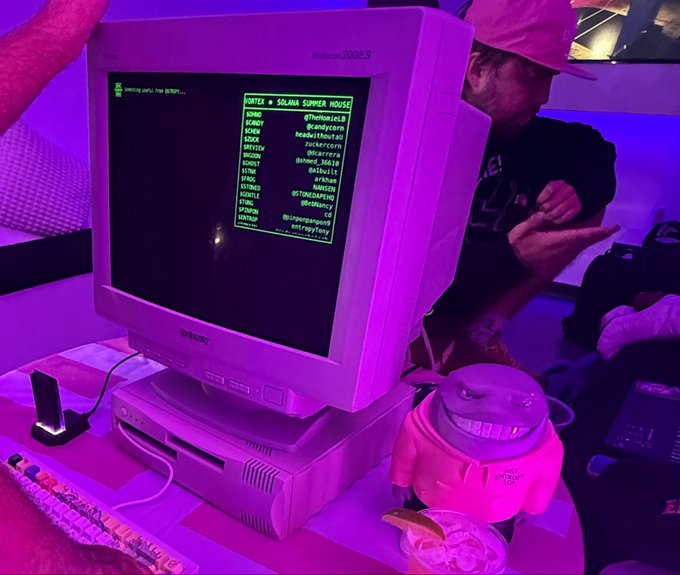 A vintage CRT monitor displays green terminal text listing "VORTEX" and "SOLANA SUPERHOUSE" at the top, with names and Twitter handles like @funkistHLB, @candvcorn, and @LickityLuna listed below, set in a purple-lit environment with a person wearing a cap in the background. The retro-futuristic aesthetic and Solana references connect to the post's mention of the Vortex event's futuristic vibes and the SSH x Entropy activation hosted by Solana Spaces.