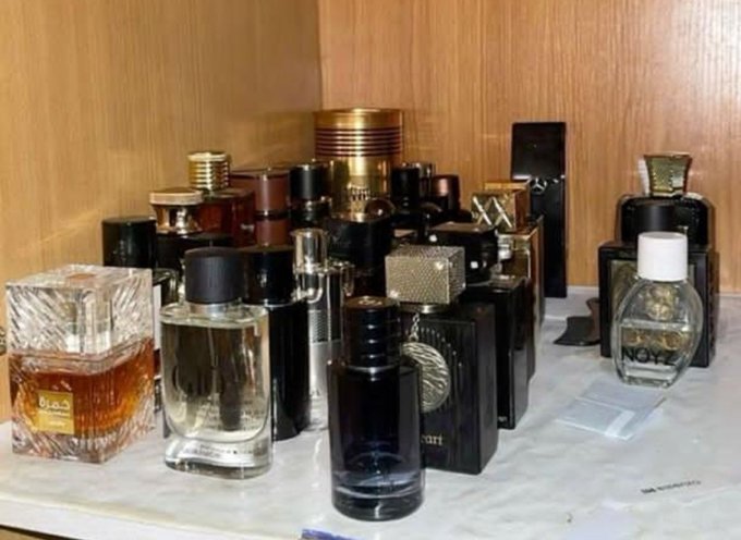 A collection of various perfume and cologne bottles arranged on a marble shelf, featuring different shapes, colors, and designs.