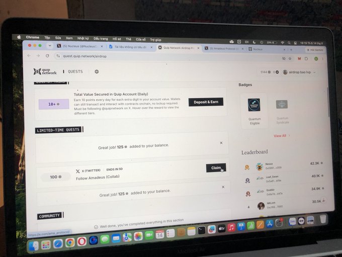 A photograph of a laptop screen displaying the Quip Network airdrop page, showing quests, badges, and a leaderboard with 'Total Value Secured in Quip Account (Daily)'.