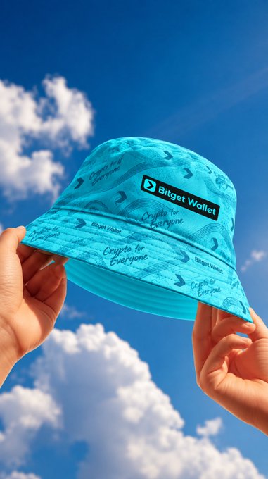 Hands hold up a teal bucket hat branded with 'Bitget Wallet' and 'Crypto for Everyone' text against a bright blue cloudy sky.