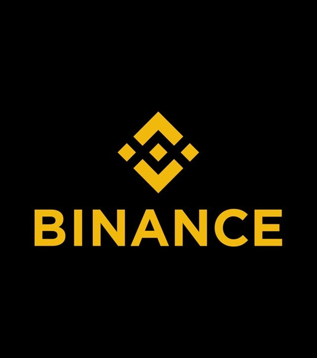 The image shows the Binance logo in gold against a black background. This logo relates to the post about UK investors filing a £150M lawsuit against Binance and Changpeng Zhao for allegedly unlawfully offering crypto derivatives to retail users despite FCA restrictions.