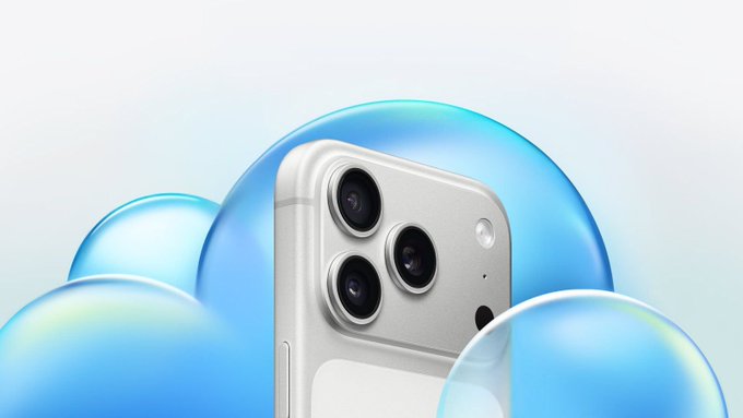 A silver smartphone with a triple-lens camera system is displayed against a light blue background featuring large, iridescent bubble graphics.