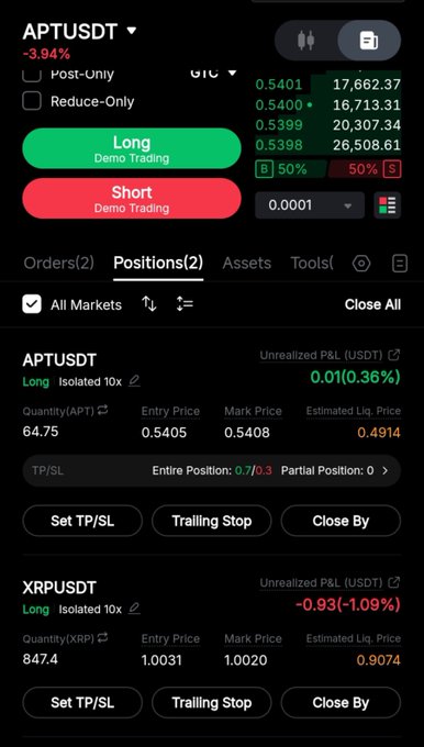 A crypto trading app interface showing APTUSDT and XRPUSDT positions with long/short demo trading options and various price data.