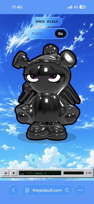 A screenshot showing a black 3D angel teddy bear character against a blue sky background, with text 'OMEN #1565' and 'thegodpull.com' visible.